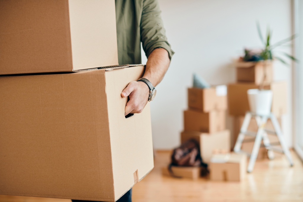 closeup-man-carrying-cardboard-boxes-while-relocating-into-new-apartment.jpg